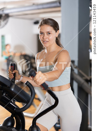Sporty girl working out on elliptical machine in gym. Healthy active lifestyle concept 121143459