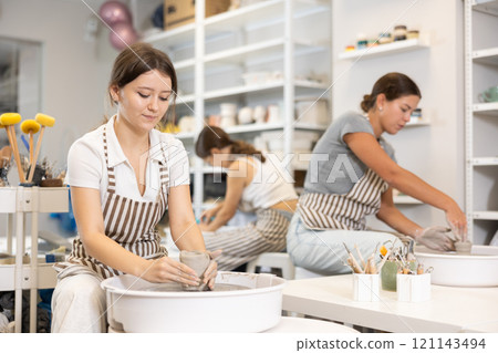 Woman teacher and students make products on potter's wheel 121143494