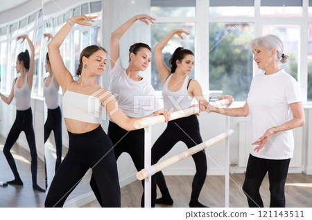 Elderly woman teacher corrects female dancers Elderly woman teacher corrects female dancers 121143511