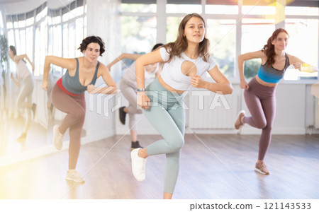 Young female teacher conducts modern dance lessons for group of girls 121143533