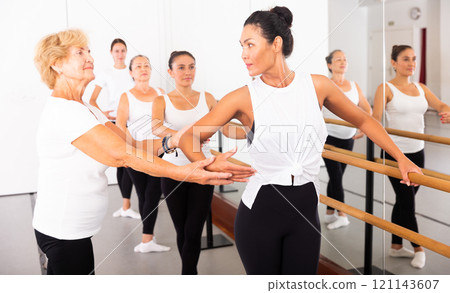Elderly ballet teacher helps female students in ballet school 121143607