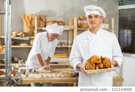 Young man are standing in kitchen with basket of finished products croissant 121143608