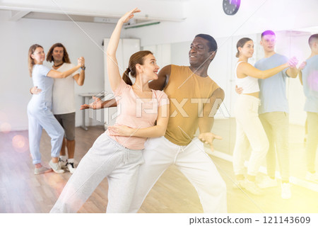 Woman and man practicing modern dance moves in pair during group class 121143609