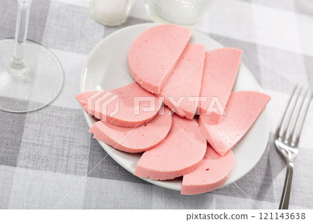 There are thick slices of boiled sausage on small round plate 121143638