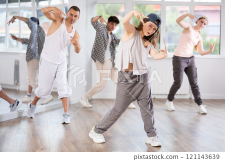 Young girl standing performs basic hip hop movements in front of group of students 121143639