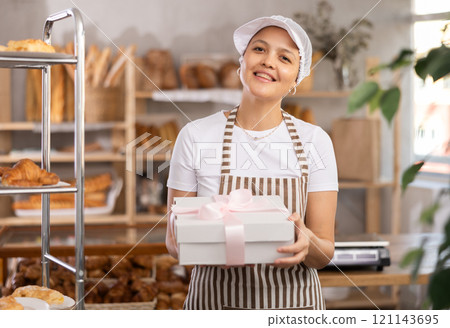 Middle-aged saleswoman holds cake box in bakery 121143695