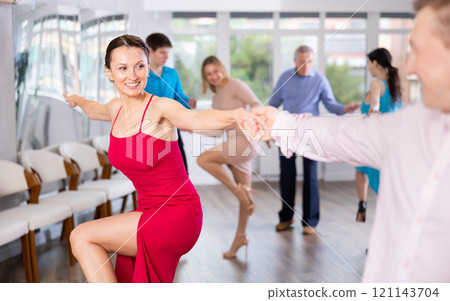Happy woman enjoying active dancing in pair in dance studio Happy woman enjoying active dancing in pair in dance studio 121143704