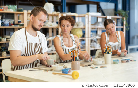 Three pottery workshop workers sculpt from raw clay Three pottery workshop workers sculpt from raw clay 121143900