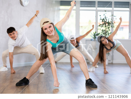 Young girl in ball cap and teenagers actively move and dance hip hop at choreography lesson Young girl in ball cap and teenagers actively move and dance hip hop at choreography lesson 121143906