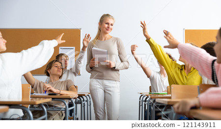 School pupils raise their hands up in classroom 121143911
