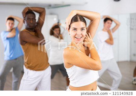 Group of active women and men practicing energetic dance in modern dance studio 121143928