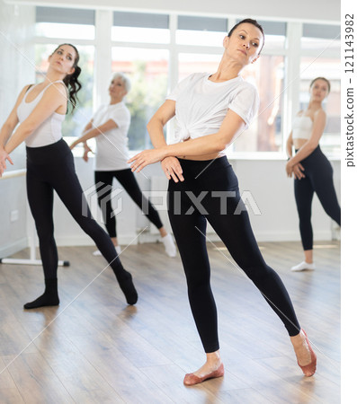 Young woman in group lesson with students rehearses, practices ballet dance, staging. 121143982