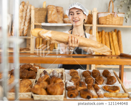 Young female seller with baguettes in bag Young female seller with baguettes in bag 121144048