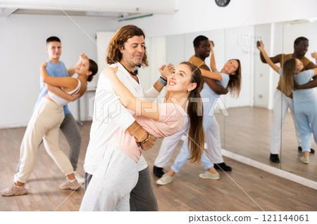 Cheerful diverse young adult people dancing together active expressive dances in pairs in modern class 121144061
