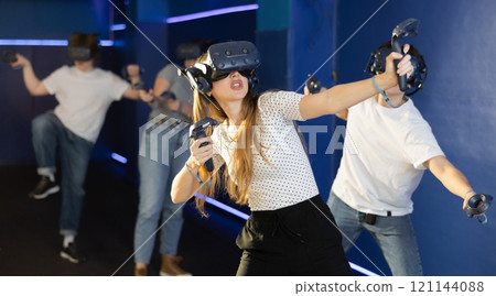 Excited young woman in VR goggles having fun in virtual reality room Excited young woman in VR goggles having fun in virtual reality room 121144088
