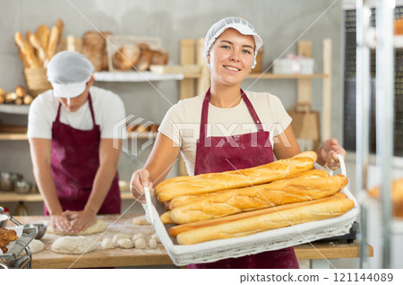 Young woman are standing in kitchen with basket of finished products baguettes Young woman are standing in kitchen with basket of finished products baguettes 121144089