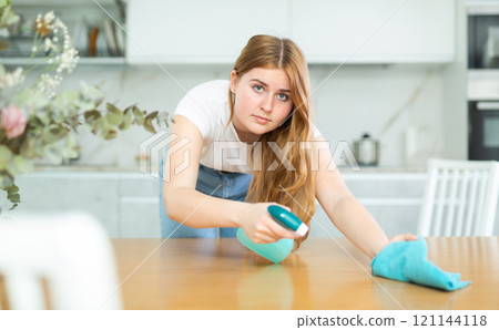 in kitchen,positive housewife in casual clothes holds rag in hands and cleans surface of table in kitchen,positive housewife in casual clothes holds rag in hands and cleans surface of table 121144118