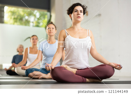 Portrait of latin american woman making yoga meditation in lotus pose in fitness studio 121144149