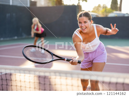Cheerful woman tennis player training on court 121144162