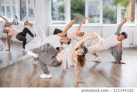 Girl and her students perform hip hop dance on one bent leg, movement in horizontal plane near floor Girl and her students perform hip hop dance on one bent leg, movement in horizontal plane near floor 121144182