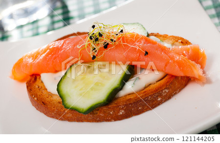 Toasted bread with creamy sauce, salmon and cucumber Toasted bread with creamy sauce, salmon and cucumber 121144205