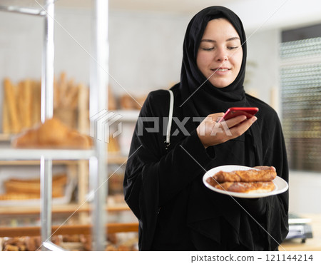 Muslim woman using phone and counting calories Muslim woman using phone and counting calories 121144214