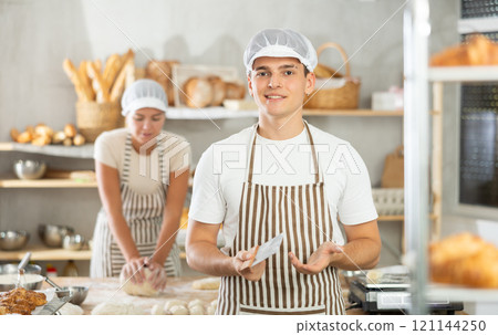 Young male baker holding a dough cutter in bakery 121144250