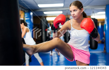 Young female practicing kicks with punching bag Young female practicing kicks with punching bag 121144343