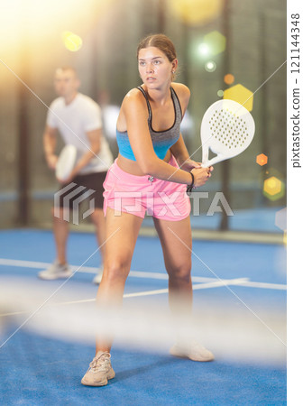Padel game - girl with partners plays on tennis court 121144348