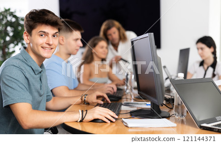 Cheerful interested guy using computer in student library Cheerful interested guy using computer in student library 121144371