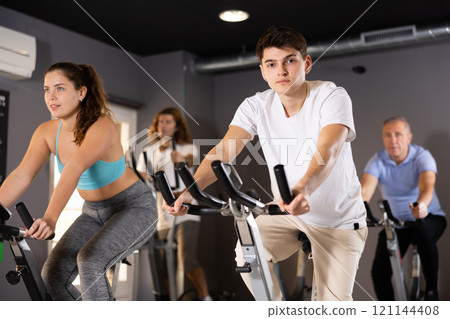 Guy doing cardio training on stationary bike in gym 121144408