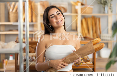 Young woman buying baguettes in bakery 121144414