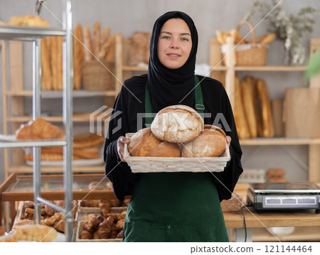 Muslim saleswoman holding a basket of bread 121144464