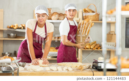 Young woman works in bakery as baker, kneads and prepare dough, works with flour. 121144483