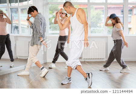 Young man standing performs basic hip hop movements in front of group of students Young man standing performs basic hip hop movements in front of group of students 121144494