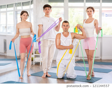 Positive sporty men and women wearing sportswear posing in fitness studio 121144557
