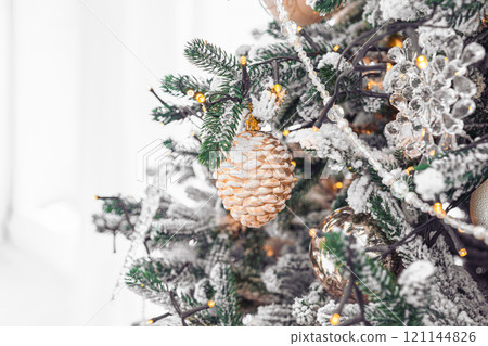 Snowy Christmas tree branch with festive lights and decorative gold and silver ornaments close up Snowy Christmas tree branch with festive lights and decorative gold and silver ornaments close up 121144826