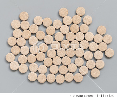 Pile of beige herbal pills  on grey top view. Taking dietary supplements and vitamin 121145180