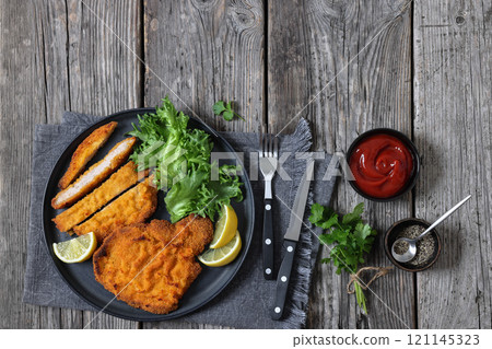 Pork Milanese with lettuce and lemon on a plate Pork Milanese with lettuce and lemon on a plate 121145323