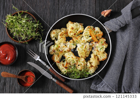 fried cauliflower florets on a skillet, top view 121145333
