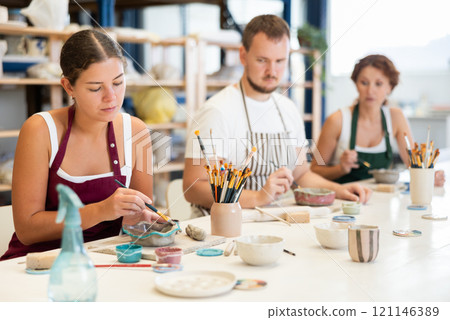 Three craftsperson are busy painting clay products Three craftsperson are busy painting clay products 121146389