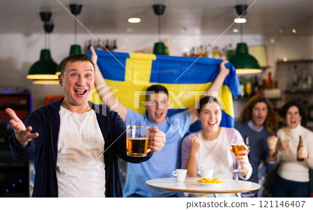 Joyful friends with the flag of Sweden celebrating the victory of their favorite team in beer bar Joyful friends with the flag of Sweden celebrating the victory of their favorite team in beer bar 121146407
