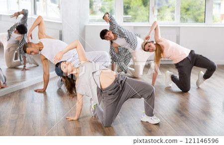 Girl and her students perform hip hop dance on one bent leg, movement in horizontal plane near floor Girl and her students perform hip hop dance on one bent leg, movement in horizontal plane near floor 121146596