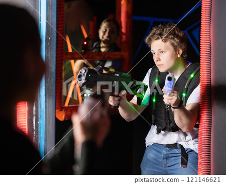 Portrait of man with laser gun having fun with family on laser tag arena 121146621