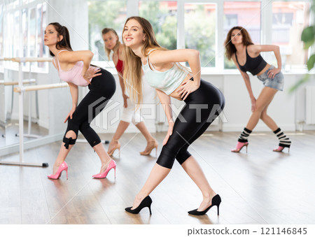 During lesson, girl learn to move and perform dance in heels with women companions During lesson, girl learn to move and perform dance in heels with women companions 121146845