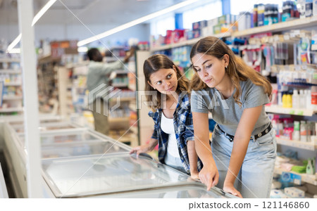 Young women choosing frozen food in supermarket 121146860