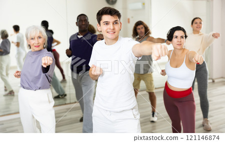 Young guy practicing punches during group self-defence workout 121146874