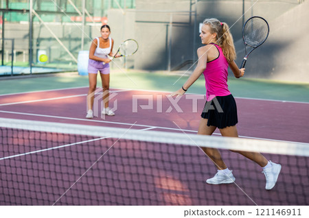Caucasian woman wearing in pink t-shirt and skirt playing tennis match during training 121146911