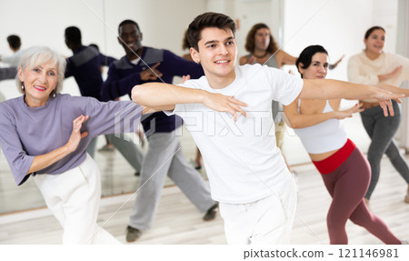 Smiling guy learning dynamic dances in group choreography class 121146981