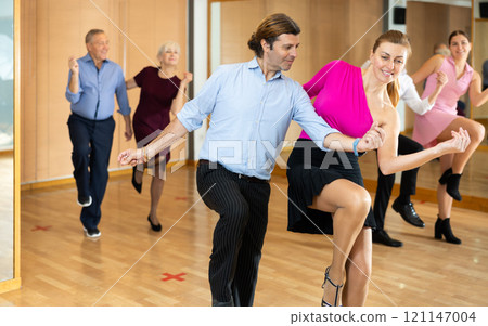 Middle-aged pair practicing Latino dance in dance studio Middle-aged pair practicing Latino dance in dance studio 121147004